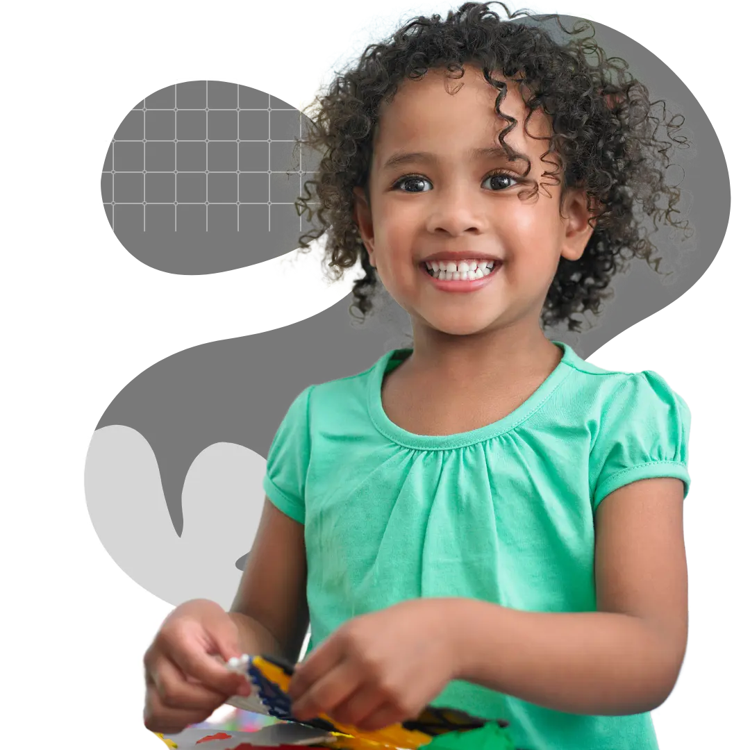 A smiling girl with curly hair wearing a green shirt holds and manipulates colorful craft materials.
