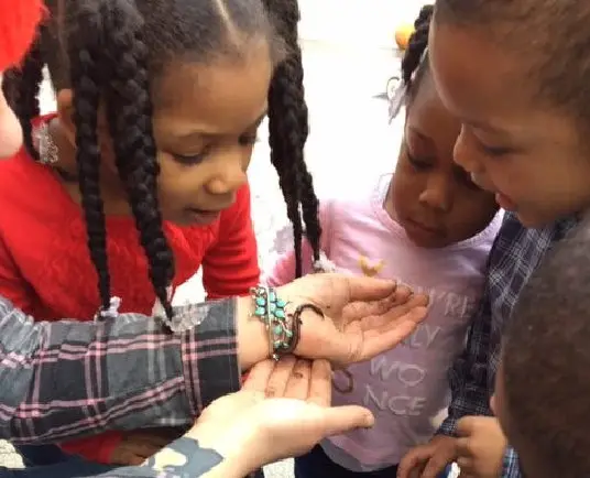 teacher showing something on her hands to the kids