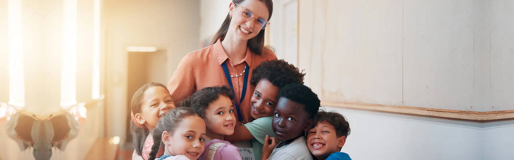 A woman and six children hugging together in a hallway.