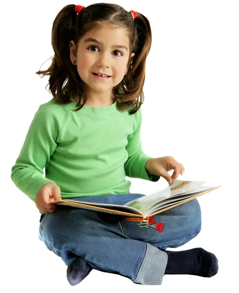 A young girl with pigtails sits cross-legged holding an open book on her lap against a black background.